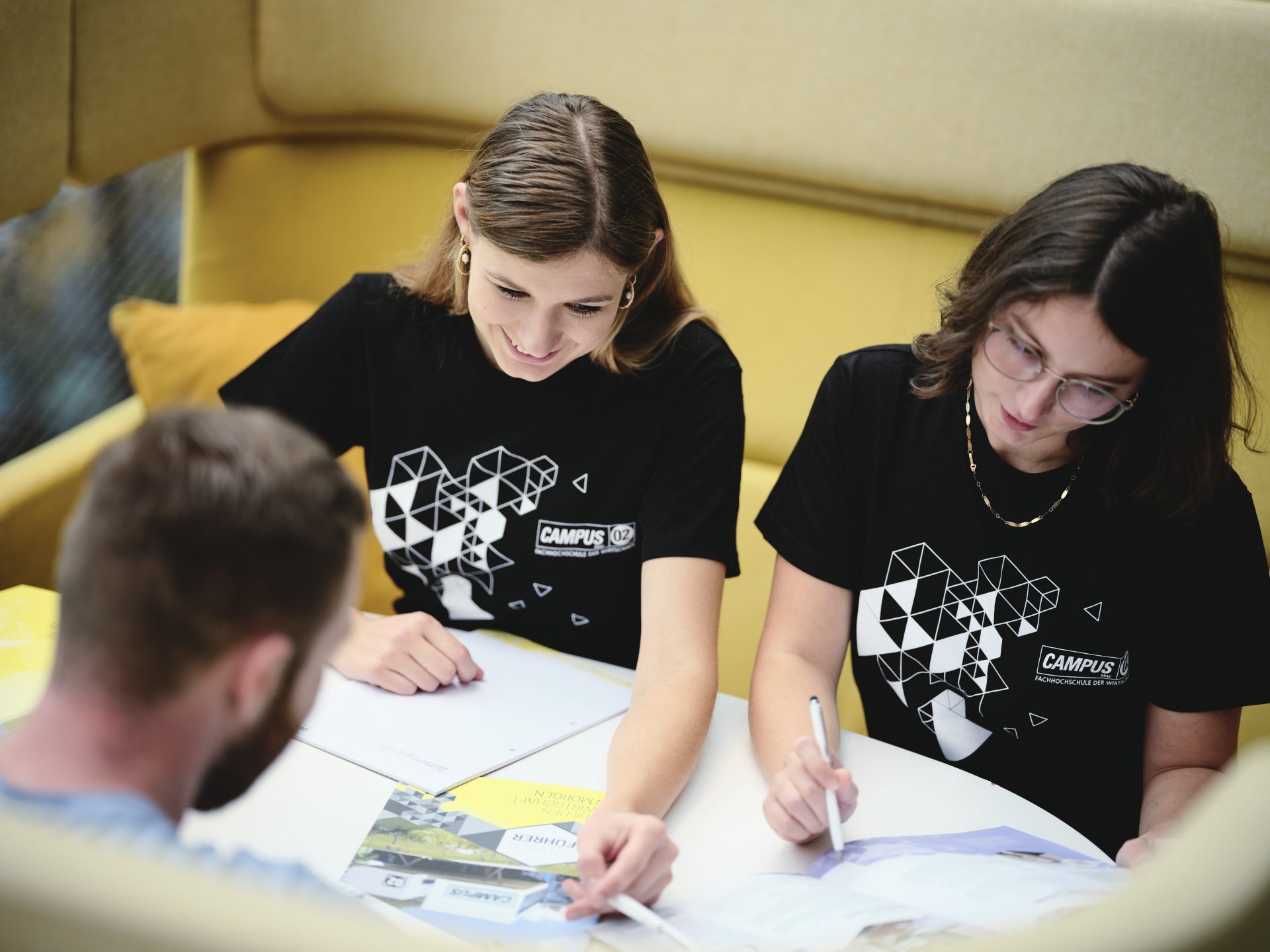 Drei Studierende am Tisch schreiben