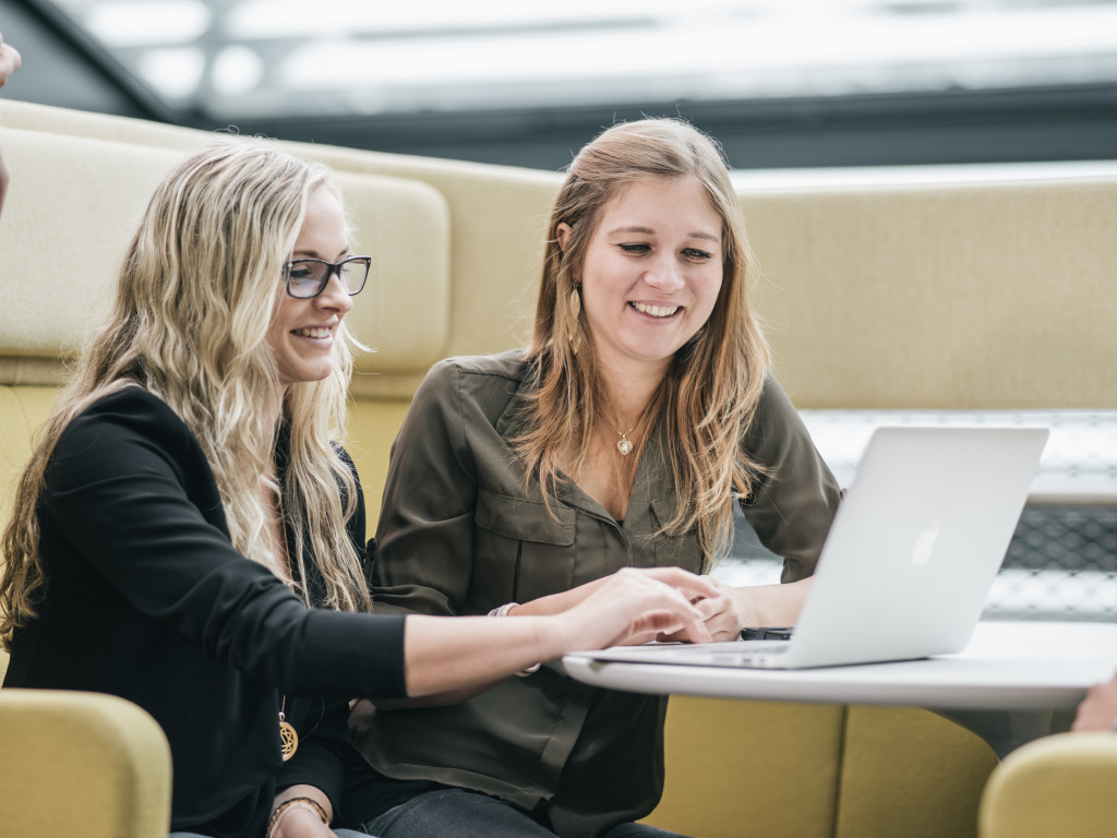 Zwei Studierende vor einem Laptop in der Aula