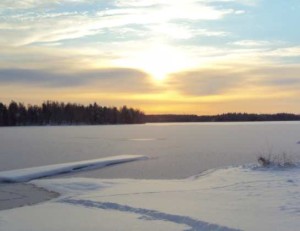Sonnenaufgang über zugefrorenem See in Finnland