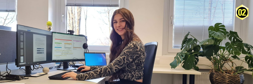 Interviewte Person, namens Lara-Sophie Brandl sitzt vor ihrem Bilschirm und lächelt dabei in die Kamera