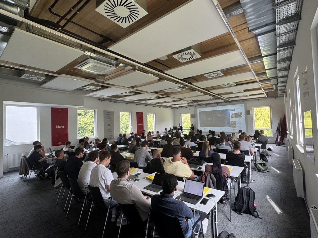 Studierende sitzen gemeinsam in einem Hörsaal und arbeiten an Gruppenarbeiten.