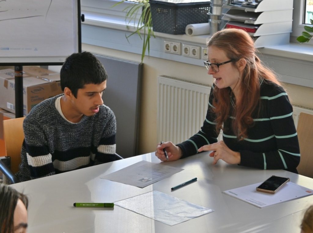 Mitarbeiterin bespricht Lebenslauf eines Teilnehmenden von AusbildungsFit