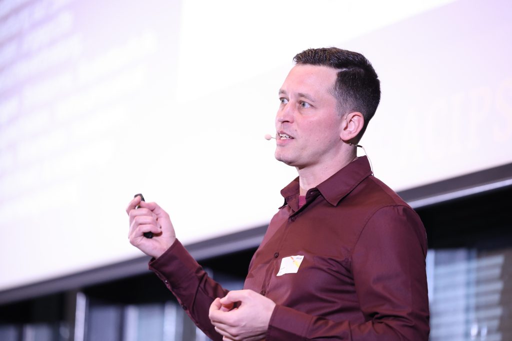 Stefan auer spricht auf der Bühne in ein Mikrofon