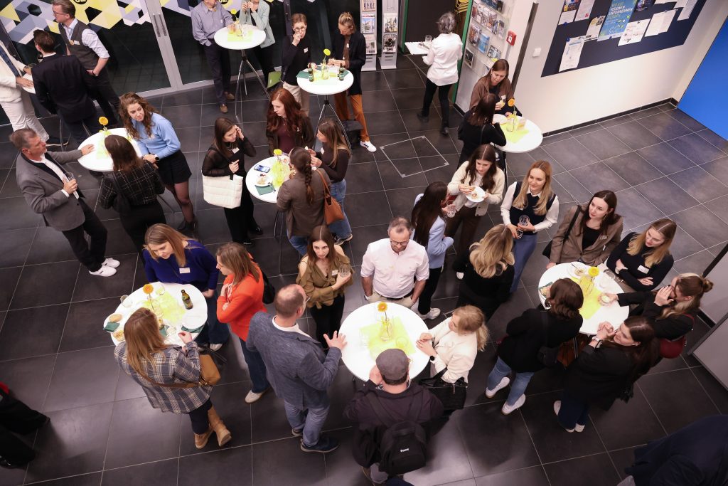 Gäste stehen an Hochtischen zusammen