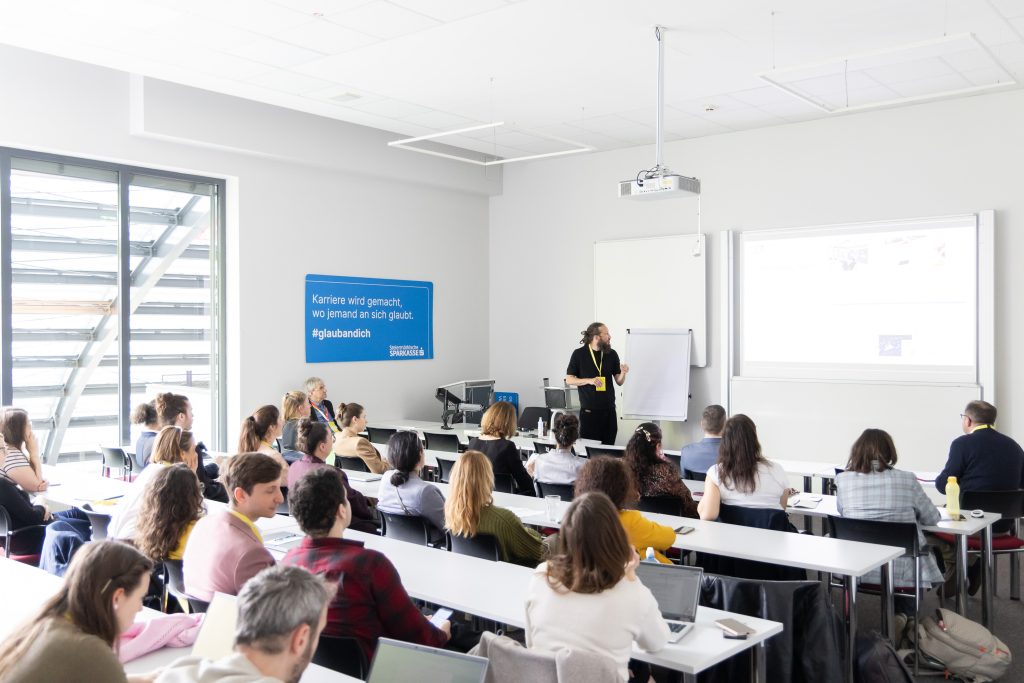 Mehrere Personen sitzen im Hörsaal bei der Präsentation eines Forschungsprojekts