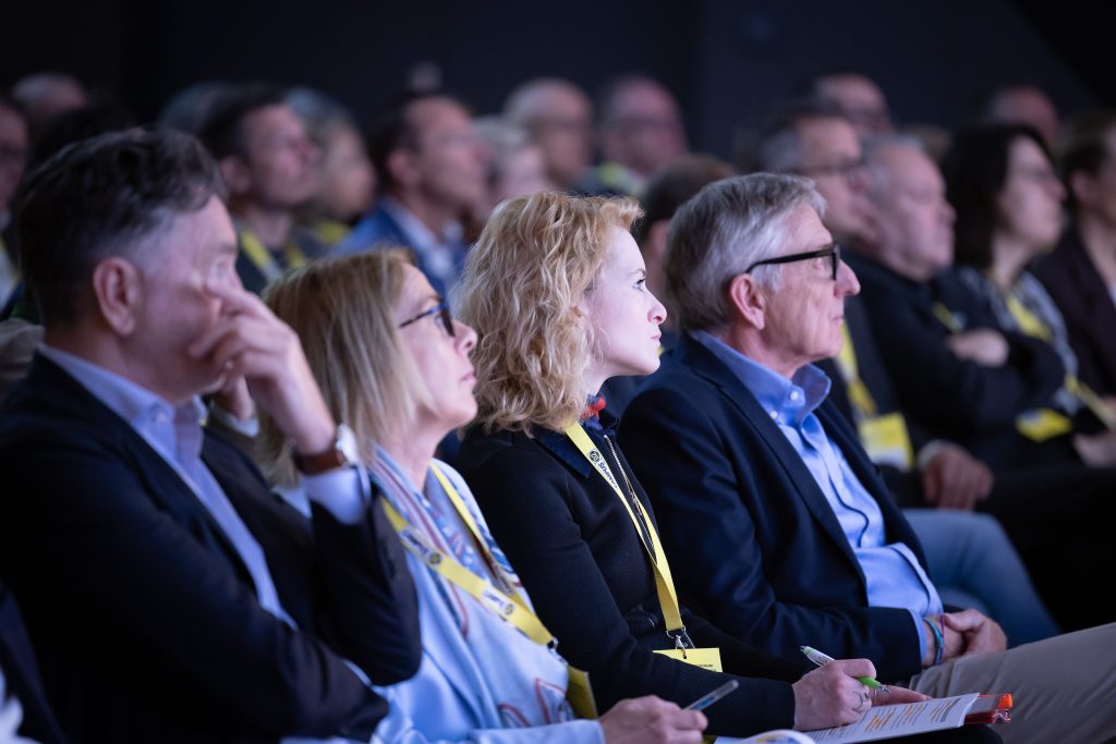 Personen sitzen im Publikum und blicken in Richtung Bühne